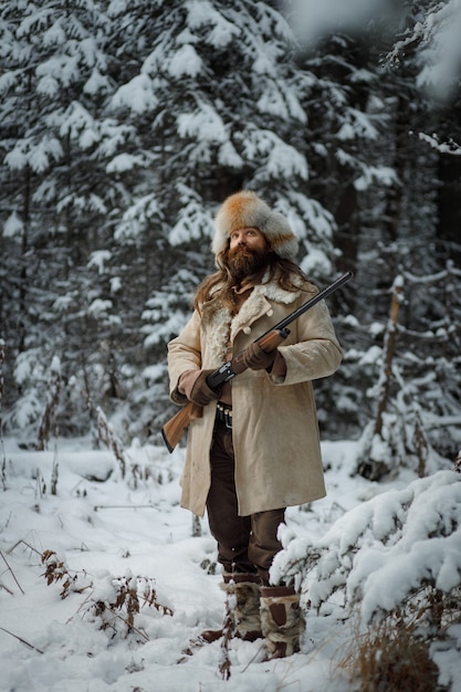 Jägermann im Winter warme Weinlesekleidung mit Pistole im Winterwald