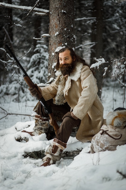 Jägermann im Winter warme Weinlesekleidung mit Pistole im Winterwald