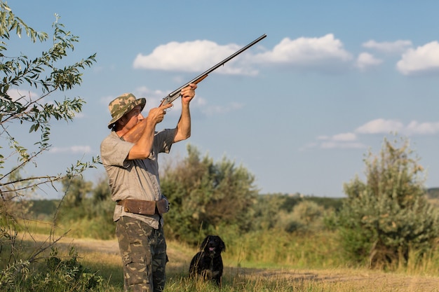 Jägermann in Tarnung mit einer Waffe während der Jagd auf der Suche nach Wildvögeln oder Wild. Jagdsaison im Herbst.