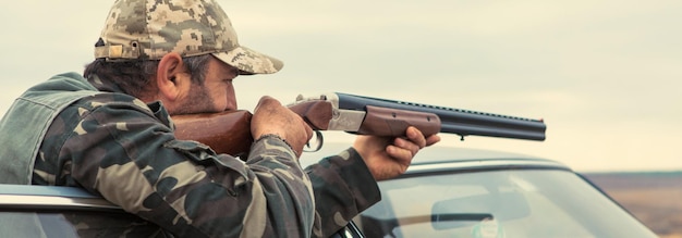 Jägermann in Tarnung mit einer Waffe während der Jagd auf der Suche nach Wildvögeln oder Wild