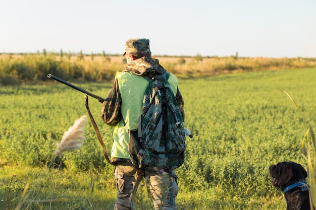 Jägermann in Tarnung mit einer Waffe während der Jagd auf der Suche nach Wildvögeln oder Wild