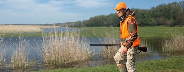 Jägermann in Tarnung mit einer Waffe während der Jagd auf der Suche nach Wildvögeln oder Wild