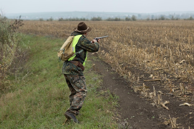 Jägermann in Tarnung mit einer Waffe während der Jagd auf der Suche nach Wildvögeln oder Wild