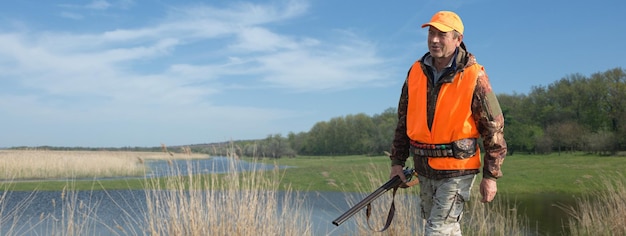 Jägermann in Tarnung mit einer Waffe während der Jagd auf der Suche nach Wildvögeln oder Wild