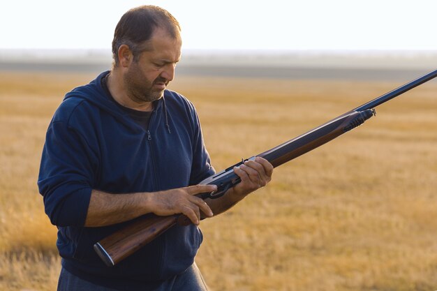 Jägermann in Tarnung mit einer Waffe während der Jagd auf der Suche nach Wildvögeln oder Wild