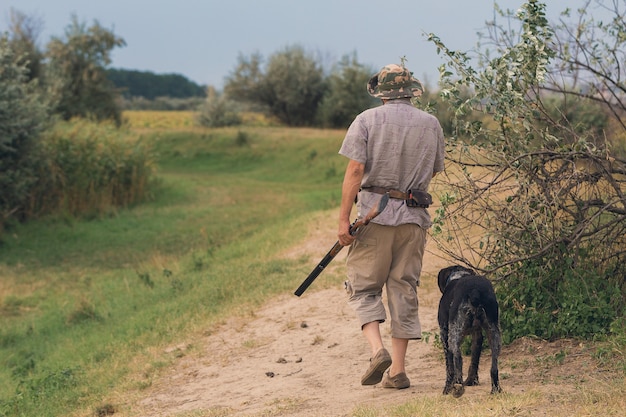 Jägermann in Tarnung mit einer Waffe während der Jagd auf der Suche nach Wildvögeln oder Wild