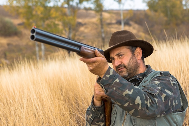 Jägermann in Tarnung mit einer Waffe während der Jagd auf der Suche nach Wildvögeln oder Wild