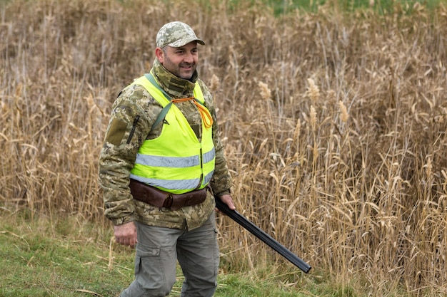 Jägermann in Tarnung mit einer Waffe während der Jagd auf der Suche nach Wildvögeln oder Wild.