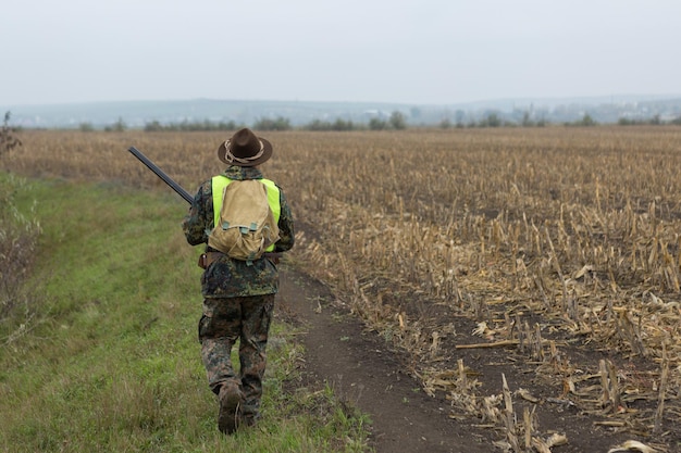 Jägermann in Tarnung mit einer Waffe während der Jagd auf der Suche nach Wildvögeln oder Wild