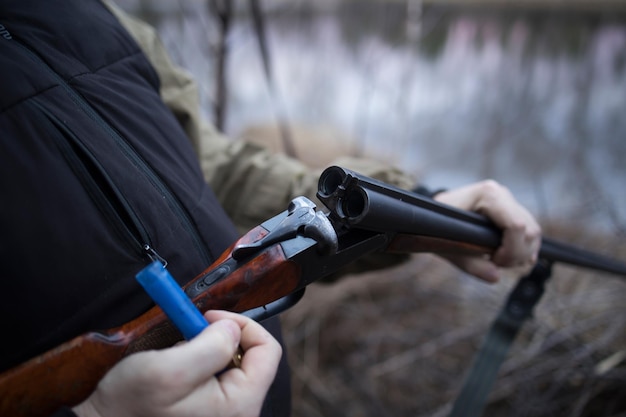 Jägermann jagt mit Gewehr am Flussufer nach Enten