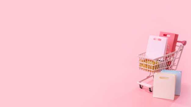 Jährlicher Verkauf Einkaufssaison Konzept Mini rosa Warenkorb Trolley voller Papiertüte Geschenk isoliert auf blassrosa Hintergrund leerer Kopierraum Nahaufnahme