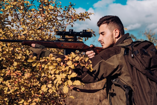 Jagd im Frühjahr Waldjäger mit Schrotflinte auf der Jagd Jäger, der sich mit Schrotflinte auf der Suche nach Beute bewegt