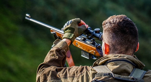 Jagdzeit. Mann mit einer Waffe. Nahaufnahme. Jäger mit Jagdgewehr und Jagdform zum Jagen. Jäger zielt. Der Mann ist auf der Jagd. Jagdgewehr jagen. Jäger Mann.