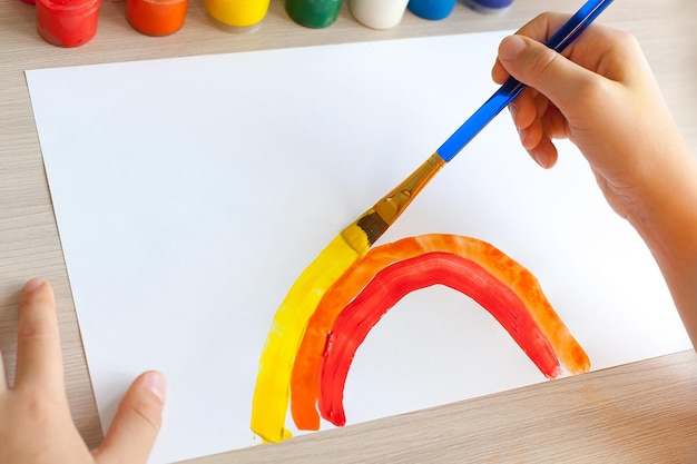 Jagen Sie den Regenbogen Kind zu Hause zeichnet einen Regenbogen auf das Fenster Kinder schaffen Künstler malt Kreativität Urlaub