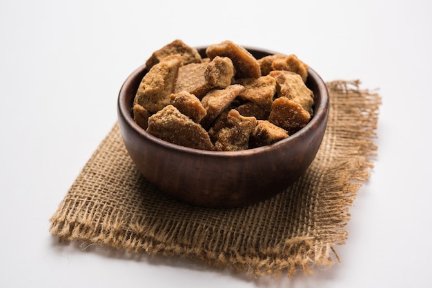 Foto jaggery o gur con caña de azúcar sobre fondo cambiante. enfoque selectivo