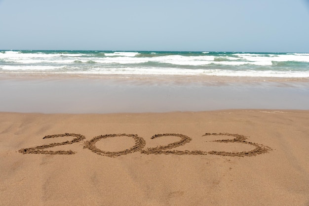 Jahr 2023 geschrieben im Sand am Strand mit dem Meer im Hintergrund