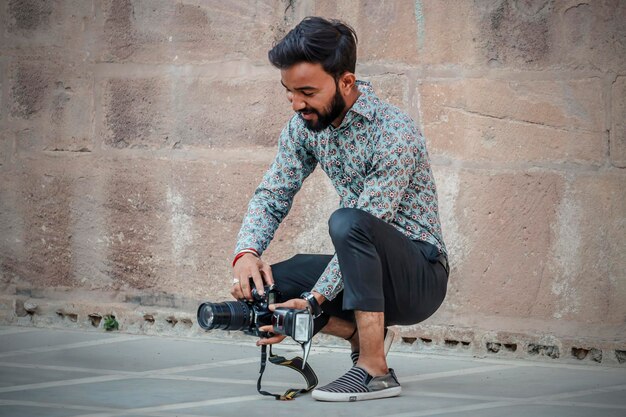 Jaisalmer, índia - 16 de março de 2020: um fotógrafo com sua câmera ao ar livre está procurando um belo ângulo de câmera.