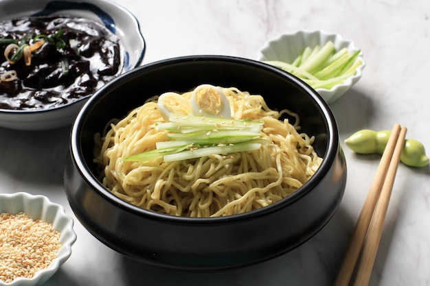 Jajangmyeon oder JJajangmyeon Korean Noddle mit schwarzer Bohnensauce, serviert mit Gurke und Sesam