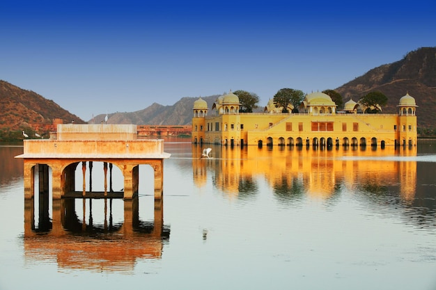 Jal mahal en el lago por las montañas contra el cielo azul claro