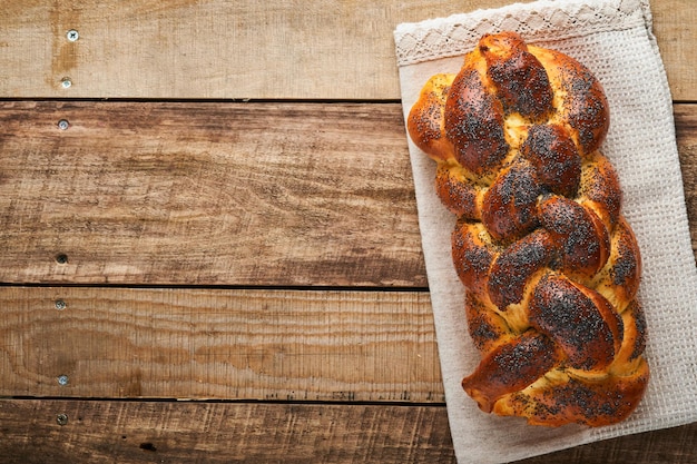 Jalá de pan Shabat Shalom con semillas de sésamo y semillas de amapola sobre fondo de madera Pan judío tradicional para Shabat y vacaciones Concepto rústico Espacio de copia Enfoque selectivo