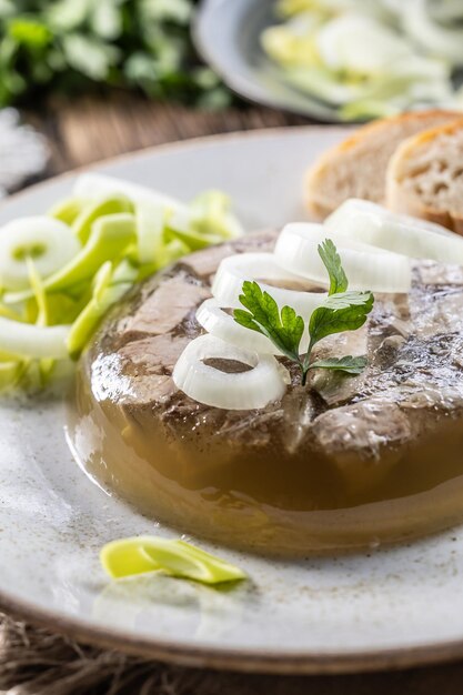 Foto jalea de carne de cerdo casera con cebolla y puré en un plato blanco