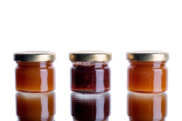 Jam em muitos frascos em um fundo branco isolado com reflexo laranja geléia de damasco conceito de maçã para publicidadexA