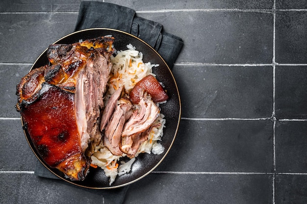 Foto jambón de cerdo asado con repollo en un plato fondo negro vista superior espacio de copia