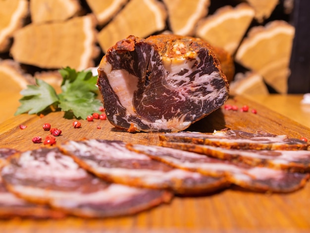 Jamón ahumado en rodajas sobre una mesa de madera con hierbas frescas y especias aromáticas