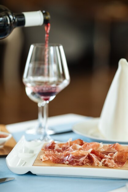 Jamón de cerdo en rodajas español con vino tinto en la mesa del restaurante