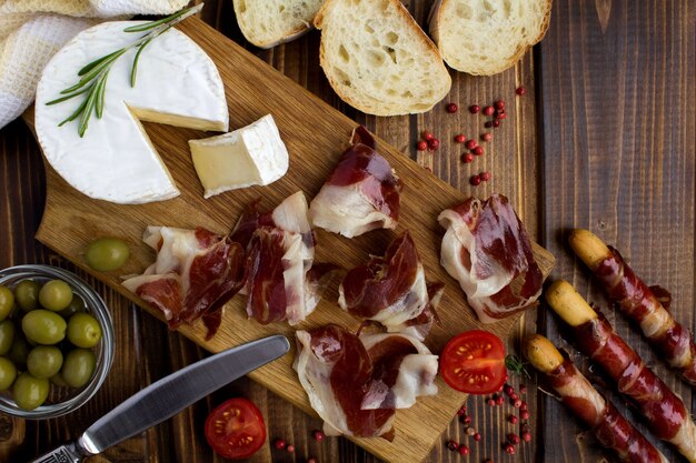 Jamón y queso en la tabla de cortar sobre el fondo de madera marrón.Vista superior.