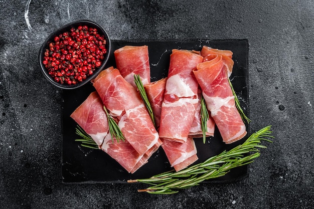 Jamón serrano tradicional español sobre tablero de mármol Fondo negro Vista superior