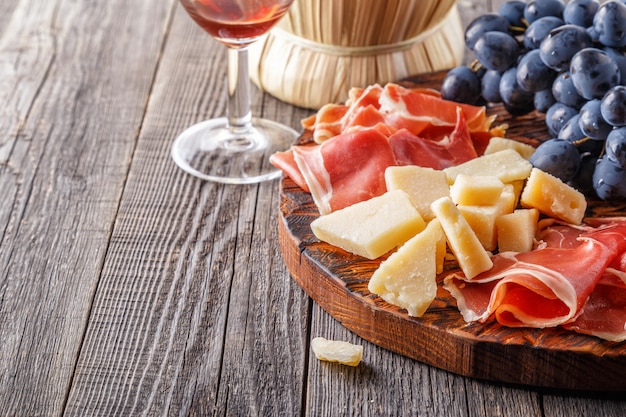 Jamón, vino, uva, parmesano en mesa de madera