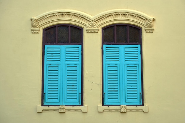 Janela antiga azul em uma parede amarela