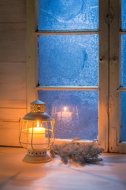 Janela azul fosco e vela acesa para o Natal