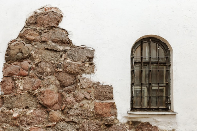 Janela com barras na parede branca. A parede da casa velha.