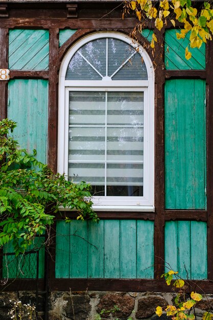 Janela de plástico em arco na velha casa de madeira verde cor