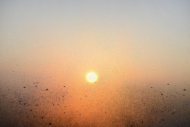 Janela de vidro embaçada com pingos de chuva, fundo desfocado. Vista da cidade e luz solar através de vidro embaçado