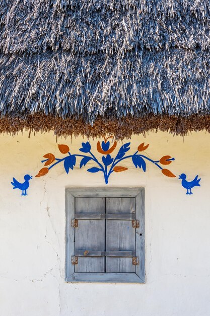 Janela vintage fechada da antiga casa ucraniana com telhado de palha