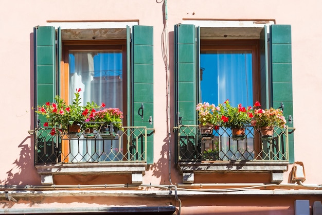 Janelas com flores em casa antiga em Veneza