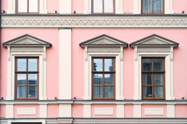 Janelas de madeira em paredes cor-de-rosa Fachada de um antigo edifício europeu da cidade