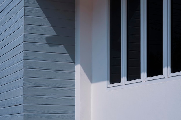 Janelas de vidro em cimento branco e parede de madeira artificial cinzenta fora do edifício da casa