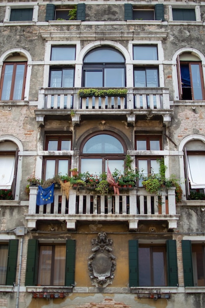 janelas em uma antiga casa decorada com flores e bandeiras, Veneza, Itália