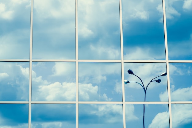 Janelas espelhadas, reflexo de nuvens e lanterna, céu azul, superfície de arranha-céus. Padrão de linha, perspectiva, estrutura de aço, abstração urbana. Forma geométrica, exterior moderno, textura da parede.