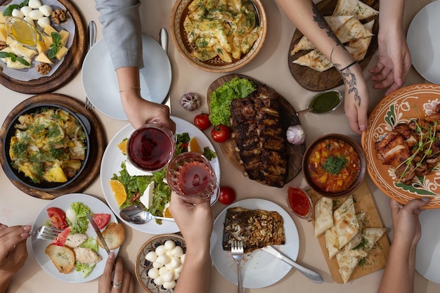 Jantar amigável Vista superior de um grupo de pessoas jantando enquanto está sentado à mesa de madeira