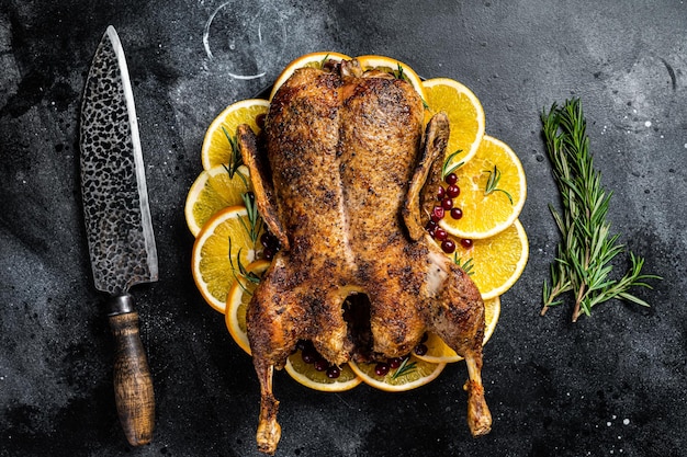 Jantar de Natal pato assado com alecrim e laranja pato assado inteiro crocante fundo preto vista superior