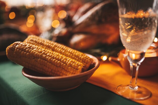 Jantar do dia de Ação de Graças com decoração de outono e velas Mesa de jantar familiar posta com delicioso peru assado dourado em travessa guarnecido com alecrim pequenas abóboras frescas