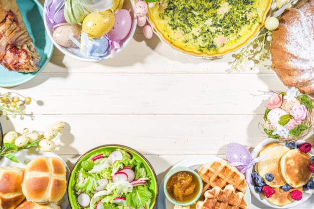 Jantar festivo, brunch de páscoa. pratos tradicionais de páscoa na mesa da casa da família - carne assada, quiche, salada primavera, muffin, ovos coloridos, pãezinhos quentes