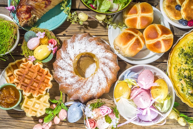 Jantar festivo, brunch de Páscoa. Pratos tradicionais de Páscoa na mesa da casa da família - carne assada, quiche, salada primavera, muffin, ovos coloridos, pãezinhos quentes