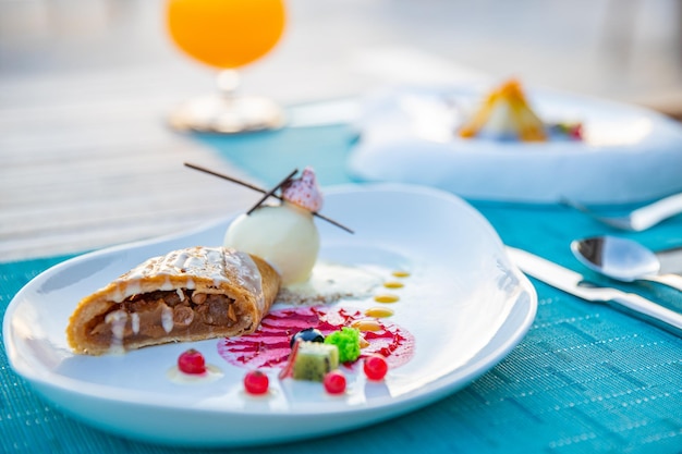 Jantar gourmet de luxo ao pôr do sol na mesa de madeira, belo resort tropical e vista para o mar, elegante