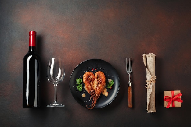 Jantar romântico com camarões e vinho coração-dados forma em um fundo marrom. Vista superior com espaço para texto